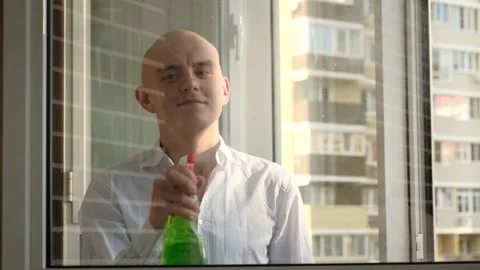 A man cleaning a window using a rag and liquid window cleaner Stock Footage 201213046