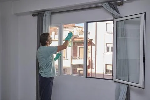 Man cleaning windows at home with sponge and spray Stock Photos