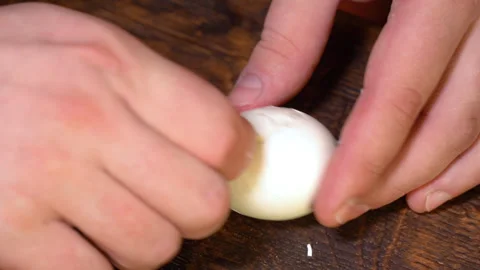 A man cleans a boiled chicken egg from the shell Stock Footage 253717735