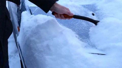 Man cleans a car of snow Stock Footage 148390333