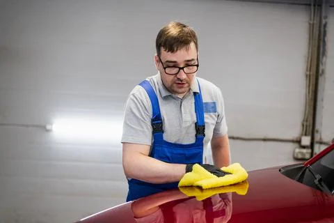 Man cleans car surface from drops using wiper. Stock Photos