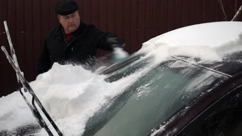A man cleans a car windshield from snow with a brush. Winter in Russia, the car Stock Footage 145771722