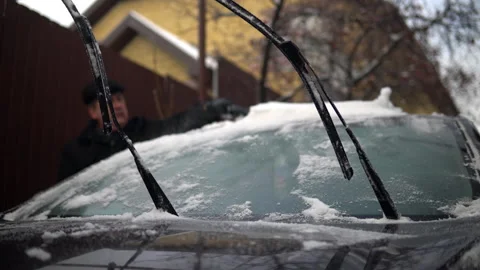 A man cleans a car windshield from snow with a brush. Winter in Russia, the car Stock-Footage 145772862