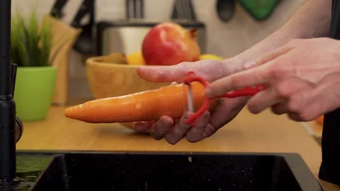 A man cleans a carrot in the kitchen 動画素材 129051264