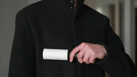 A man cleans clothes with a sticky roller, close-up Stock-Footage 240434437