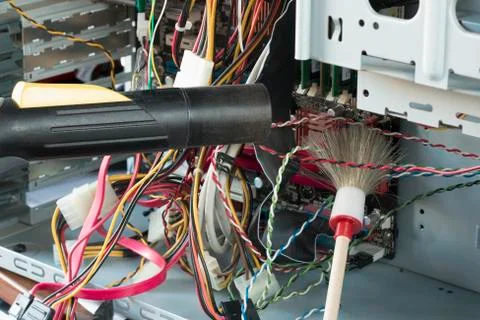 Man cleans the computer with a brush and vacuum cleaner from dust and dirt. Stock Photos