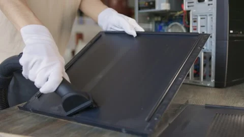 A man cleans a computer case with a vacuum in a bright room, stressing workspace Stock Footage 309822534