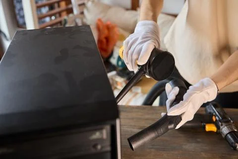 A man cleans a computer case with a vacuum in a bright room, stressing workspace Stock Photos