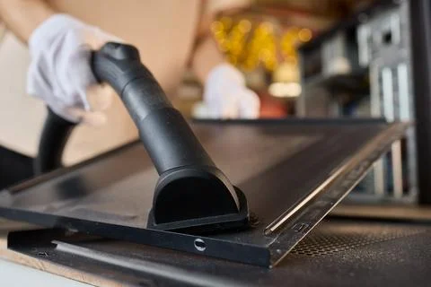 A man cleans a computer case with a vacuum in a bright room, stressing workspace Stock Photos