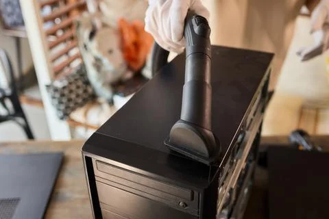 A man cleans a computer case with a vacuum in a bright room, stressing workspace Stock Photos