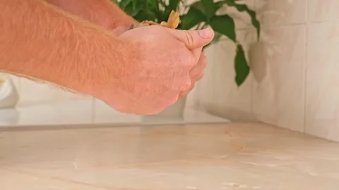 A man cleans dried fish in the kitchen. The guy separates the meat and bones of Stock Footage 245657439
