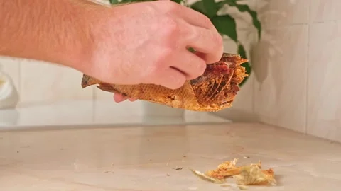 A man cleans dried fish in the kitchen. The guy separates the meat and bones of Stock Footage 246641543