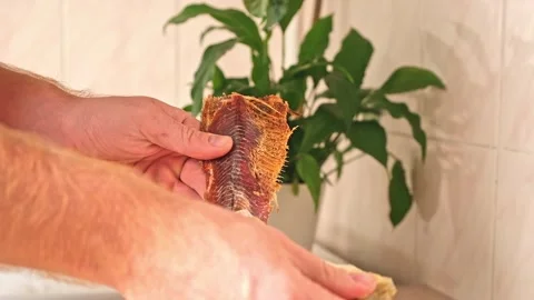 A man cleans dried fish in the kitchen. The guy separates the meat and bones of Stock Footage 246915664