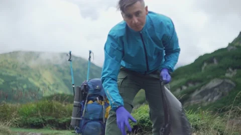 A man cleans the environment, collects garbage in nature in the mountains Stock Footage 218440158