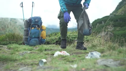 A man cleans the environment, collects garbage in nature in the mountains Stock Footage 218441286