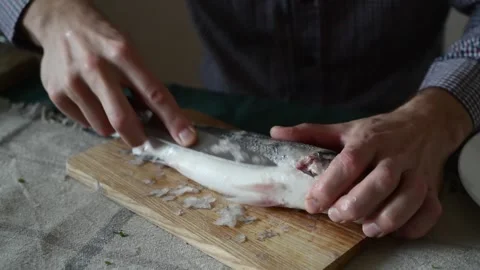A man cleans fish from scales with a knife Stock Footage 320012313