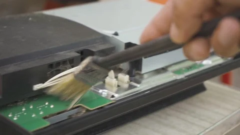 A man cleans the game console board from dust with a brush Stock Footage 108563783