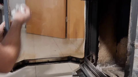 A man cleans glass by a fireplace from soot Vídeos de archivo 100728586