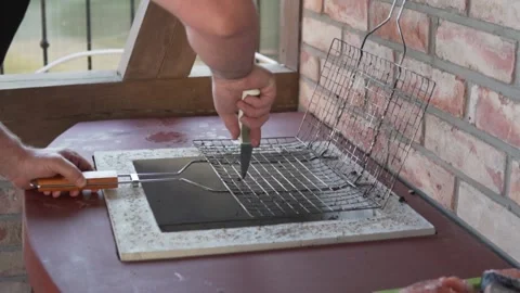 The man cleans the grate of the remnants of the kebab with a knife Stock Footage 158040692