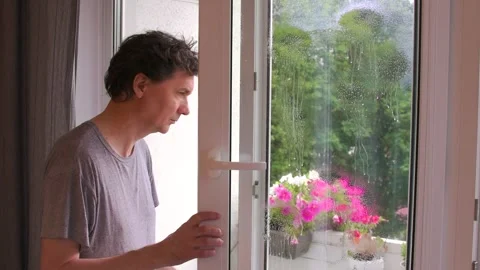A man cleans his apartment windows using a spray bottle. He stands by the o.. Stock Footage 343549512