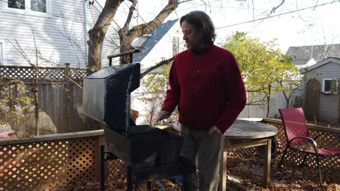 A man cleans his BBQ medium  shot Stock Footage 142276797
