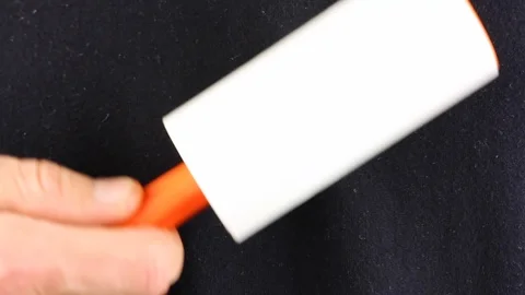 Man cleans his black clothes with adhesive roller to cleaning cloth Видео 102889936