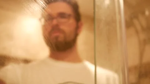 Man cleans the inside of shower class door in modern tile shower Stock Footage 219261623