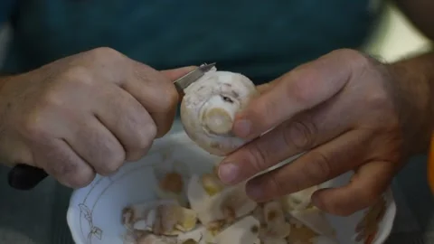 A man cleans mushrooms with a knife. Stock Footage 233447054