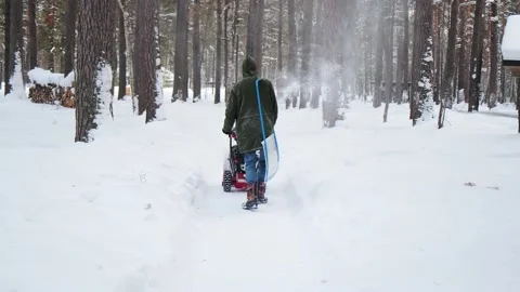 Man cleans park road walking with snow blower and shovel 스톡 동영상 134235397