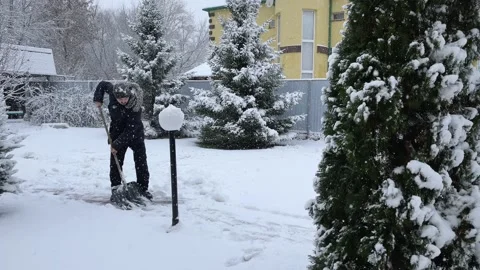 Man cleans the path from snow with a shovel. Snow is falling Stock-Footage 221714360