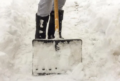 A man cleans the paths in the yard from snow. Stock Photos
