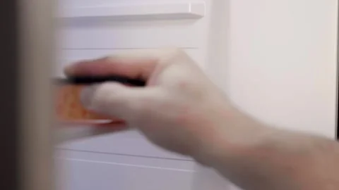 Man cleans up  a refrigerator shelf. Kitchen chores. Man cleaning fridge with sp Video stock 305341700