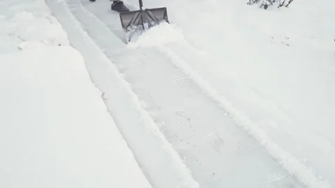 A man cleans the road of snow with a gray plastic shovel Stock Footage 170256682