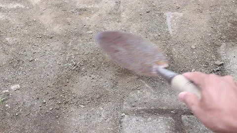 A man cleans the sand on the cement paving floor using a small shovel Stock Footage 182211809