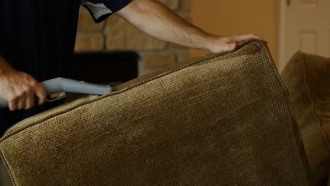 Man cleans the side of a green couch cushion with steam cleaner profile shot  Video stock 85869909