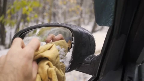 Man cleans side mirror from snow sitting in car on road Stock Footage 143331349