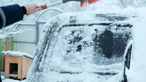 A man cleans snow from a car with a brush. Stock Footage 168057163