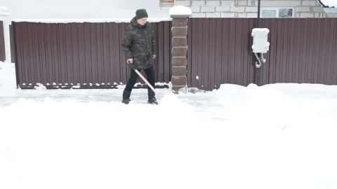 Man cleans the snow-covered road with a shovel Video stock 101389170
