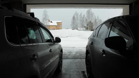 Man cleans snow with a snow thrower. View from two car from garage Video stock 125821029