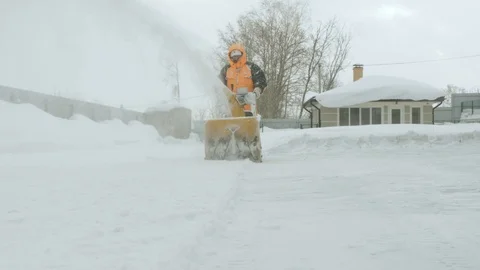 Man cleans snow with a snow thrower. Movement on camera Stock Footage 125822058