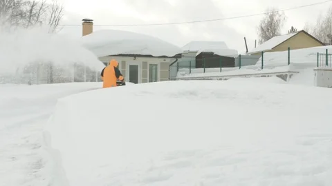 Man cleans snow with a snow thrower behind a snowdrift Stock Footage 125822291