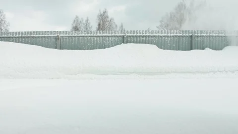 Man cleans snow with a snow thrower goes right to left static camera Stock Footage 125823077
