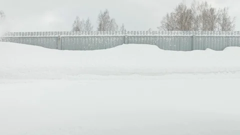 Man cleans snow with a snow thrower goes left to right static camera Stock Footage 125823204
