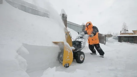 Man cleans snow with a snow thrower. Pushing mashine Video stock 125825690