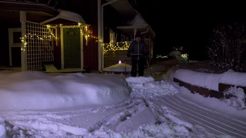 A man cleans snow in the winter on path from house towards camera Stock Footage 254367007