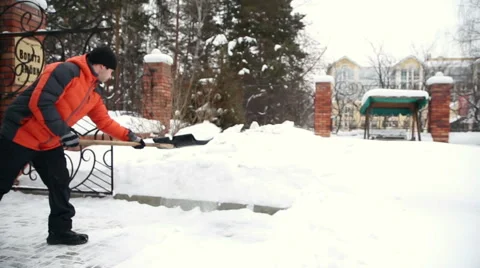 A man cleans snow in the yard after a snowfall Stock-Footage 61405056