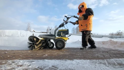 Man cleans snow in the yard with a sweeper in the winter Видео 125824541