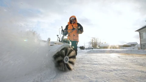 Man cleans snow in the yard with a sweeper in the winter Stock Footage 125824654