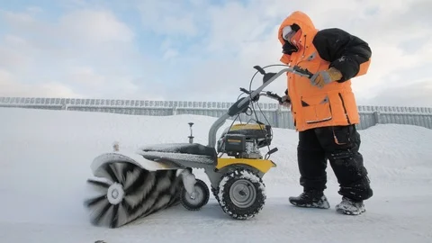 Man cleans snow in the yard with a sweeper in the winter Vídeo Stock 125825155
