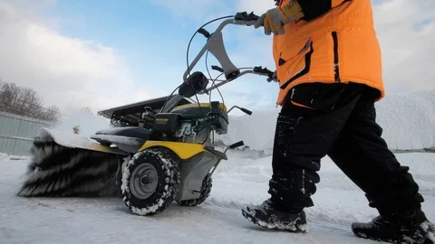 Man cleans snow in the yard with a sweeper in the winter 스톡 동영상 125825427